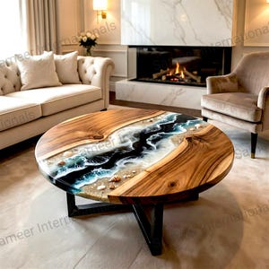 Puede incluir: Mesa de centro redonda de madera con un diseño único de resina epoxi. La mesa presenta un diseño similar a un río con resina azul, blanca y negra, conchas marinas y arena. La mesa está soportada por una base de metal negro.