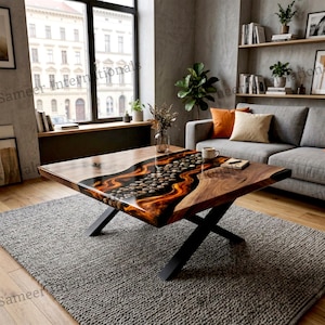 Puede incluir: Una mesa de centro rectangular con un diseño único. La mesa presenta una tapa de madera con un río de piedras y resina naranja. Tiene patas de metal negro y se apoya sobre una alfombra gris. La mesa mide unos 122 cm de largo.