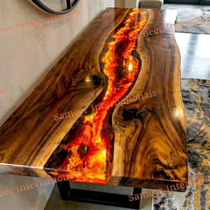 Puede incluir: Una taza de cerámica blanca con un asa negra y el texto "But First, Coffee" en negrita negra. La taza se encuentra sobre un fondo borroso, sugiriendo un ambiente acogedor.