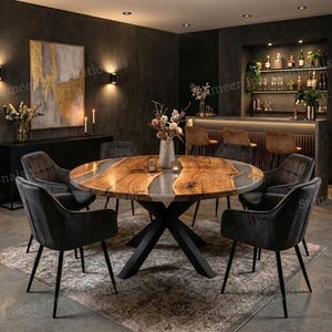 以下が含まれることがあります： 天然木の天板にグレーの樹脂インレイを施した円形ダイニングテーブルで、黒いX字型の金属製脚部で支えられています。テーブルの周りには、黒い金属製の脚を持つダークグレーの布張りアームチェアが6脚、模様入りのラグの上に配置されています。