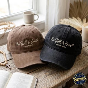 Peut inclure: Deux casquettes de baseball, une marron et une noire, arborant toutes deux le texte brodé en blanc Be Still & Know et Psalm 46:10 avec un petit symbole de cœur. Les casquettes présentent une calotte structurée, une visière courbée et un fini usé.