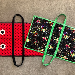 May include: Two fabric tote bags. One bag is red with black polka dots and white flower accents. The other bag is black with green trim and a colorful confetti pattern.