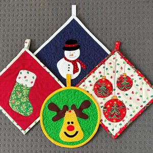 May include: Four Christmas-themed pot holders. One is red with a green stocking, one is blue with a snowman, one is white with red and green ornaments, and one is green with a reindeer.