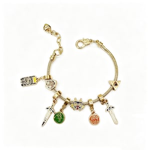 Pode incluir: Pulseira de berloques dourada com vários berloques coloridos. Os berloques incluem espadas, escudos e desenhos circulares com detalhes em verde, laranja e vermelho. A pulseira tem um fecho de lagosta e uma corrente ajustável.