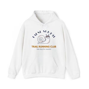 May include: White hooded sweatshirt with a front pocket and drawstring. The front features a graphic of a snail wearing a hat, with the words "FALSE SUMMIT" above and "TRAIL RUNNING CLUB (we stop for snacks)" below.