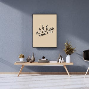 May include: A rectangular framed wall art piece with a light beige background. It features a black line drawing showing the evolution of a human life from a crawling infant to a person walking toward a coffin, with the text HAVE FUN printed below.