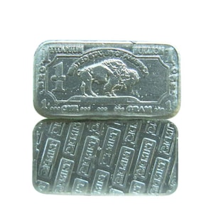 May include: Two rectangular silver-colored metal bars. The top bar features a buffalo, the text UNITED STATES OF AMERICA, and the number 1. The bottom bar displays a repeating pattern of the text CICKMINT embossed diagonally across the surface.