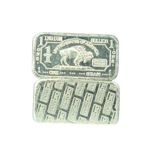 May include: Two silver bullion bars. The top bar features a buffalo image, the text "UNITED STATES OF AMERICA", and "1 OUNCE". The bottom bar has a repeating pattern of the text "CMO MINT".