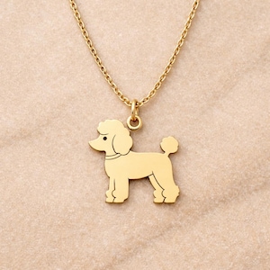 Può includere: Una collana con ciondolo a forma di barboncino color oro. Il ciondolo è una silhouette di un cane barboncino. La catena e il ciondolo della collana sono in metallo dorato lucido. Il barboncino ha una coda soffice e una testa riccia.
