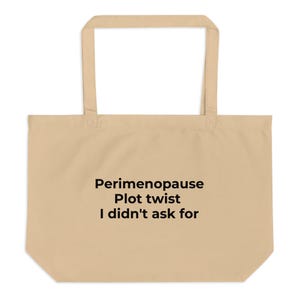 May include: A beige tote bag with long handles. The bag features the text "Perimenopause Plot twist I didn't ask for" in black, centered on the front. The bag is made of a sturdy fabric, suitable for carrying items.
