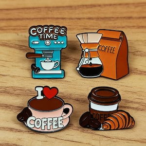 May include: Set of four coffee-themed enamel pins. Designs include a blue espresso machine with "Coffee Time" text, a pour-over coffee maker, a pink coffee cup with "I Love Coffee" text, and a coffee cup with a croissant.