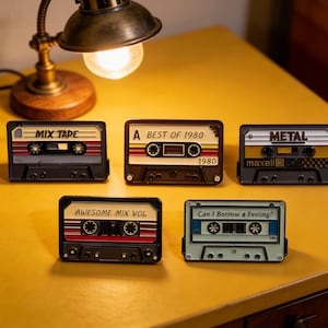 May include: Five retro cassette tape designs with text including "MIX TAPE", "BEST OF 1980", "METAL", "AWESOME MIX VOL", and "Can I Borrow a Feeling?". Each tape has a unique color scheme, with black, brown, and gray cases.