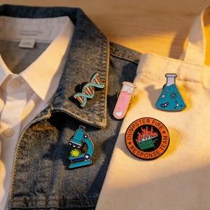 Peut inclure: Plusieurs épingles émaillées sur le thème de la science et de l'humour. Les épingles incluent une double hélice d'ADN, une éprouvette avec un cœur, un flacon avec des molécules, un microscope et un badge "Dumpster Fire Response Team".