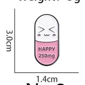 May include: A white and pink enamel pin shaped like a capsule, with a smiling face on the top half. The bottom half reads "HAPPY 250mg". The pin is 1.4 cm wide and 3.0 cm tall, and weighs 3g.