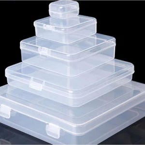 Pu&ograve; includere: Una pila di cinque contenitori di plastica trasparente di diverse dimensioni. Ogni contenitore ha una forma rettangolare con coperchio incernierato e chiusura di sicurezza. I contenitori sono disposti a forma di piramide.