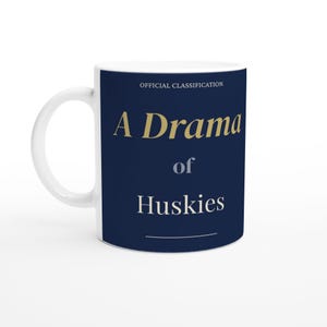 May include: White ceramic mug with the text "A Drama of Huskies" in gold and white lettering on a navy blue background. The mug also has the words "OFFICIAL CLASSIFICATION" at the top.
