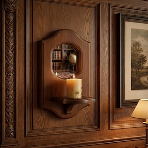 May include: A wall-mounted wooden candle sconce featuring a central circular mirror and a small integrated shelf. A single cream-colored pillar candle with a lit wick sits on the shelf, reflecting in the mirror which shows a library background.