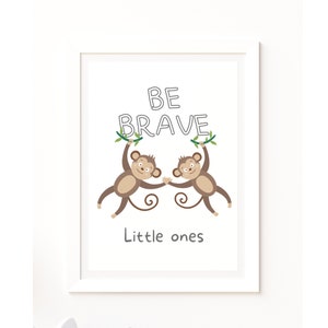 Op de afbeelding: Een witte ingelijste print met twee bruine apen die aan een wijnstok hangen met de woorden "BE BRAVE" erop. De tekst "Little ones" staat onder de apen.