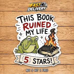 May include: A die-cut sticker featuring a green frog covering its eyes with its hands next to a burning book. The text reads THIS BOOK RUINED MY LIFE and 5 STARS! in black and red lettering. The design includes small star accents and black outlines.