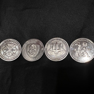 May include: Four silver coins with detailed relief designs. The coins feature various emblems, including a caduceus, a shield with a flame, a trident with wings, and a soldier with a dog. The coins are displayed on a black surface.