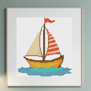 Puede incluir: Un punto de cruz enmarcado de un velero sobre agua azul. El barco es amarillo con un mástil marrón y una vela con rayas rojas y blancas. Una pequeña bandera roja ondea desde lo alto del mástil. La obra de arte está en un marco blanco.