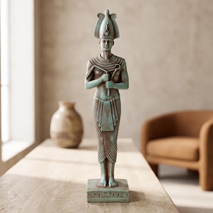Peut inclure: Une statue turquoise et brune représentant un pharaon égyptien portant une haute coiffe et un large collier. La figure tient un sceptre et un fléau sur la poitrine, porte un pagne plissé et se tient sur une base rectangulaire avec des hiéroglyphes.