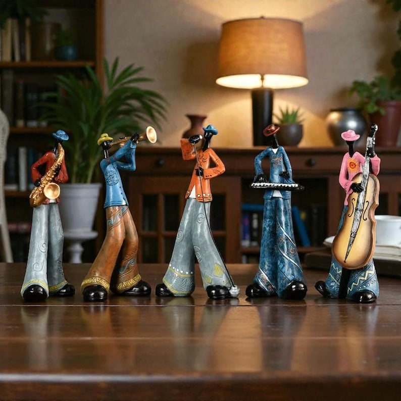 May include: A set of five decorative figurines of jazz musicians. Each figure is playing a different instrument, including a saxophone, trumpet, microphone, keyboard, and double bass. The figurines are dressed in colourful outfits and stand on a wooden table.