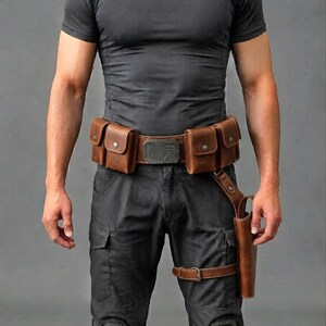 K&ouml;nnte beinhalten: Ein brauner Leder-G&uuml;rtel mit vier rechteckigen Taschen, die &uuml;ber Metall-Druckkn&ouml;pfe verf&uuml;gen, und einer zentralen Metallschnalle. Ein passendes Lederholster ist am G&uuml;rtel befestigt und reicht mit einem verstellbaren Riemen bis zum Oberschenkel.
