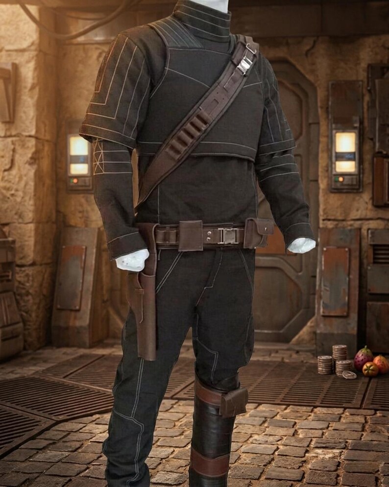 May include: A black costume with a high collar, short sleeves, and a brown leather strap across the chest. The costume includes matching trousers, a belt with a holster, and a brown leather accent on the leg. The outfit is displayed on a mannequin.