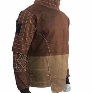 May include: Brown jacket with a high collar and contrasting panels. The jacket features white stitching details and a black patch on the upper sleeve. The lower portion of the jacket is a lighter brown color.