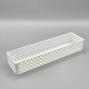 May include: A white rectangular storage box with a geometric triangle design. The box is made of a solid material and has a long, narrow shape. The sides are perforated with small triangular cutouts.