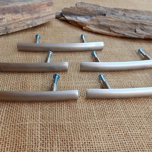 May include: Six brushed nickel cabinet pulls with a curved design. Each pull has two screws for installation.