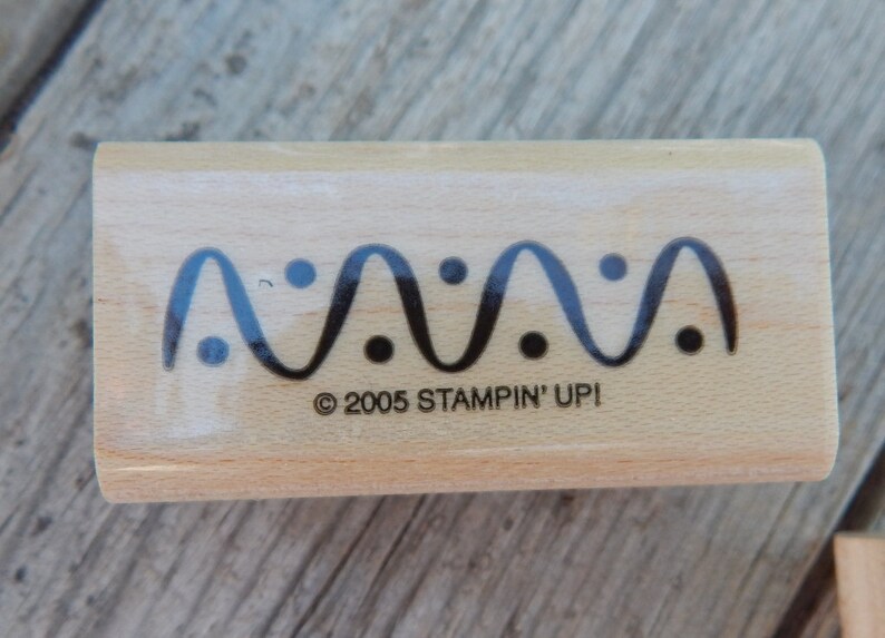 Peut inclure: Un tampon en bois avec un motif de ligne ondul&eacute;e et des points noirs. Le texte "&copy; 2005 STAMPIN' UPI" est imprim&eacute; sur le tampon.