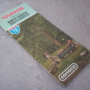 May include: A vintage Touraide road map of North Dakota and South Dakota, featuring a blue and white highway sign with the number 78. The map is advertising Conoco.