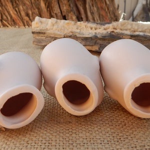 May include: Three unfinished porcelain doll heads, each with a round opening at the bottom. The heads are light pink and have a smooth, matte finish.