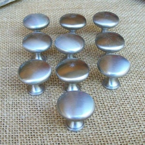 May include: Twelve silver cabinet knobs with a round, slightly domed shape and a short, cylindrical base.