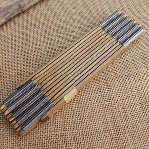 May include: A wooden folding ruler with metal measuring sections. The ruler is closed and has a natural wood finish.