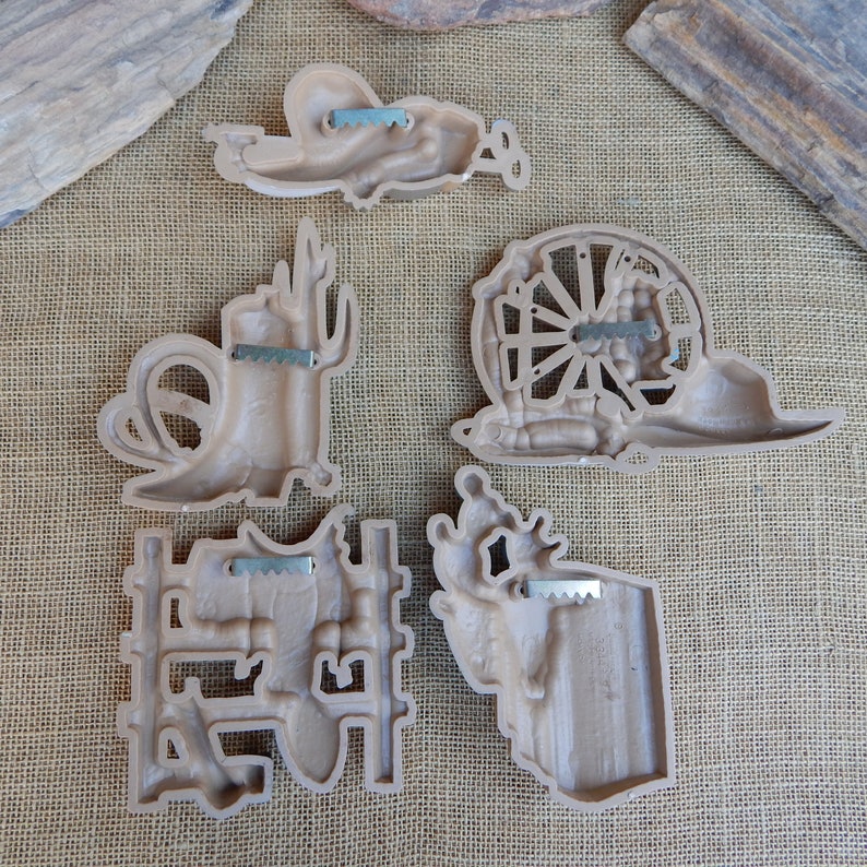 May include: Set of six brown plastic wall decor pieces with a western theme. The pieces include a cactus, a horseshoe, a wagon wheel, a cowboy boot, a cowboy hat, and a steer skull.