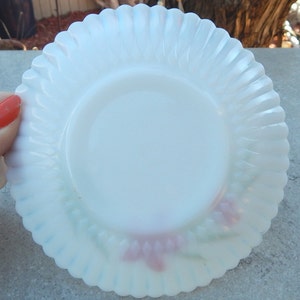 May include: A white milk glass saucer with a scalloped edge and a floral design in pink and green.