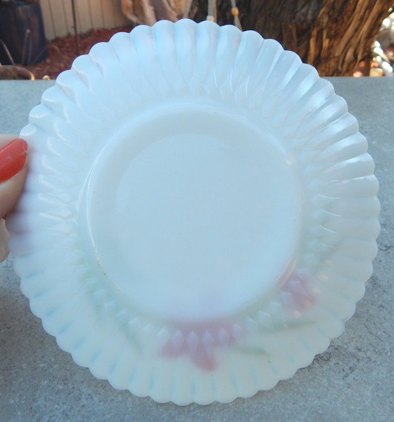 May include: A white milk glass saucer with a scalloped edge and a floral design in pink and green.
