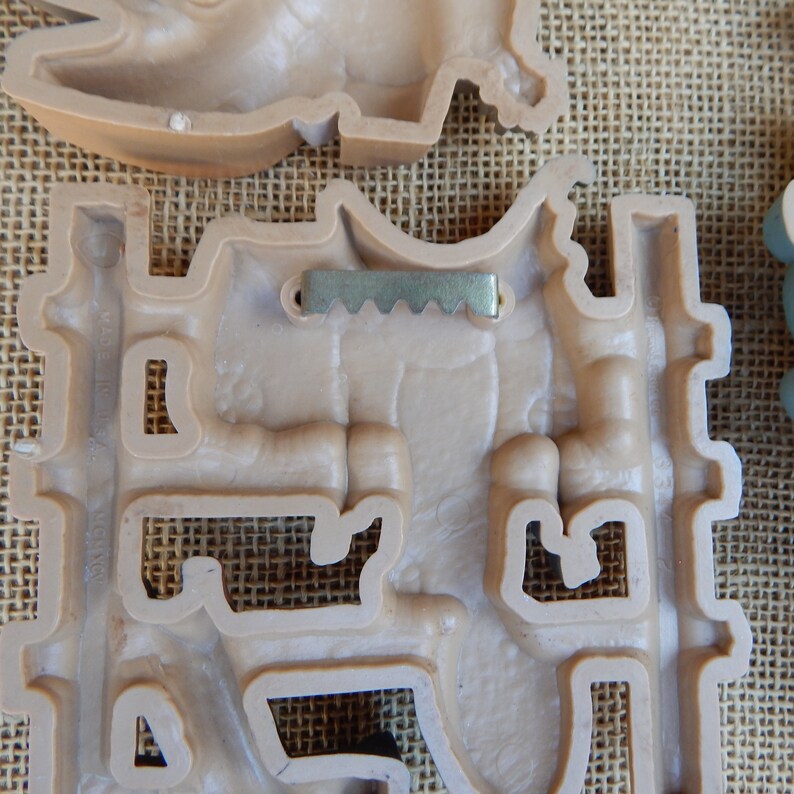 May include: A beige plastic wall decor with a metal hanging hook. The decor is shaped like a castle with a tower and a gate. The decor has a textured surface.