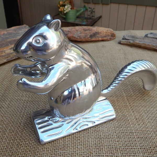 May include: A silver squirrel nutcracker with a detailed tail and a base that resembles a tree stump.