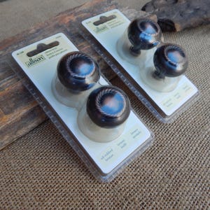May include: Two packages of oil-rubbed bronze cabinet knobs. Each package contains two round knobs with a rope-like design. The knobs are displayed on white cards with the "Allison" logo and product information.