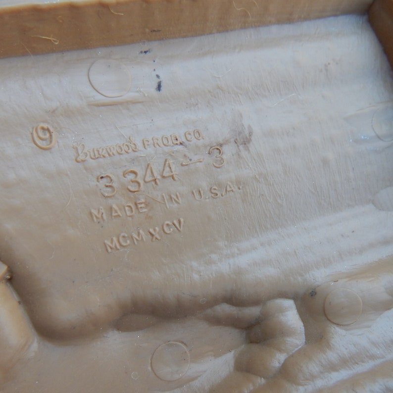 May include: Close-up of a brown plastic toy with the text "Buckwood Prod. Co. 3344-3 Made in U.S.A. MCMXCV" printed on the bottom.