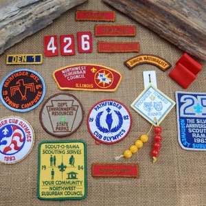 May include: A collection of colorful embroidered patches with various designs and text, including "Pathfinder Dist", "Northwest Suburban Council", "Scout-O-Rama", "Progress Toward Ranks", "The Silver Anniversary Scout-O-Rama 1963", and "Junior Naturalist".