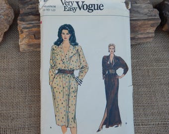 Peut inclure: Un patron de couture Very Easy Vogue vintage. Le patron présente des illustrations de deux femmes portant des robes. La robe de gauche est de style trench-coat beige avec des pois colorés. La robe de droite est une longue robe marron avec une fente haute.