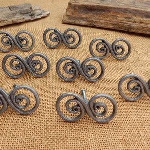 May include: Eight silver-toned cabinet knobs with a decorative infinity symbol design. The knobs are arranged in a semi-circle on a brown burlap surface.