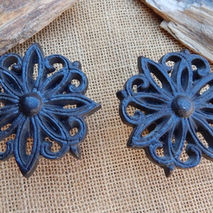 Puede incluir: Dos pomos de puerta decorativos de hierro fundido negro con un diseño floral.