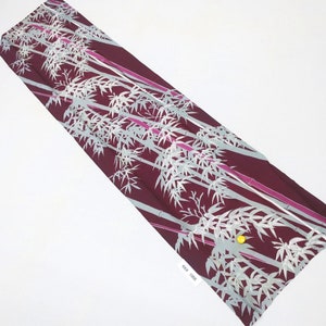 May include: A burgundy fabric with a repeating pattern of white bamboo stalks and leaves. The fabric has a subtle pink sheen.