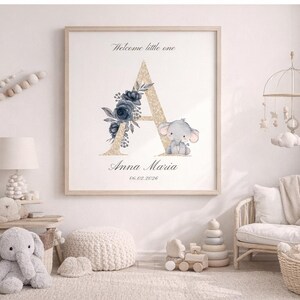 Könnte beinhalten: Ein gerahmter Kinderzimmerdruck mit einem goldglitzernden Buchstaben "A", marineblauen floralen Akzenten und einer grauen Elefantenillustration. Der Text "Welcome little one" sowie ein Name und ein Datum sind ebenfalls enthalten.